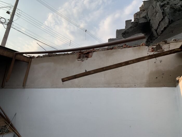 Vista interna de edificação danificada com parede parcialmente destruída devido à queda de muro de arrimo em Londrina.