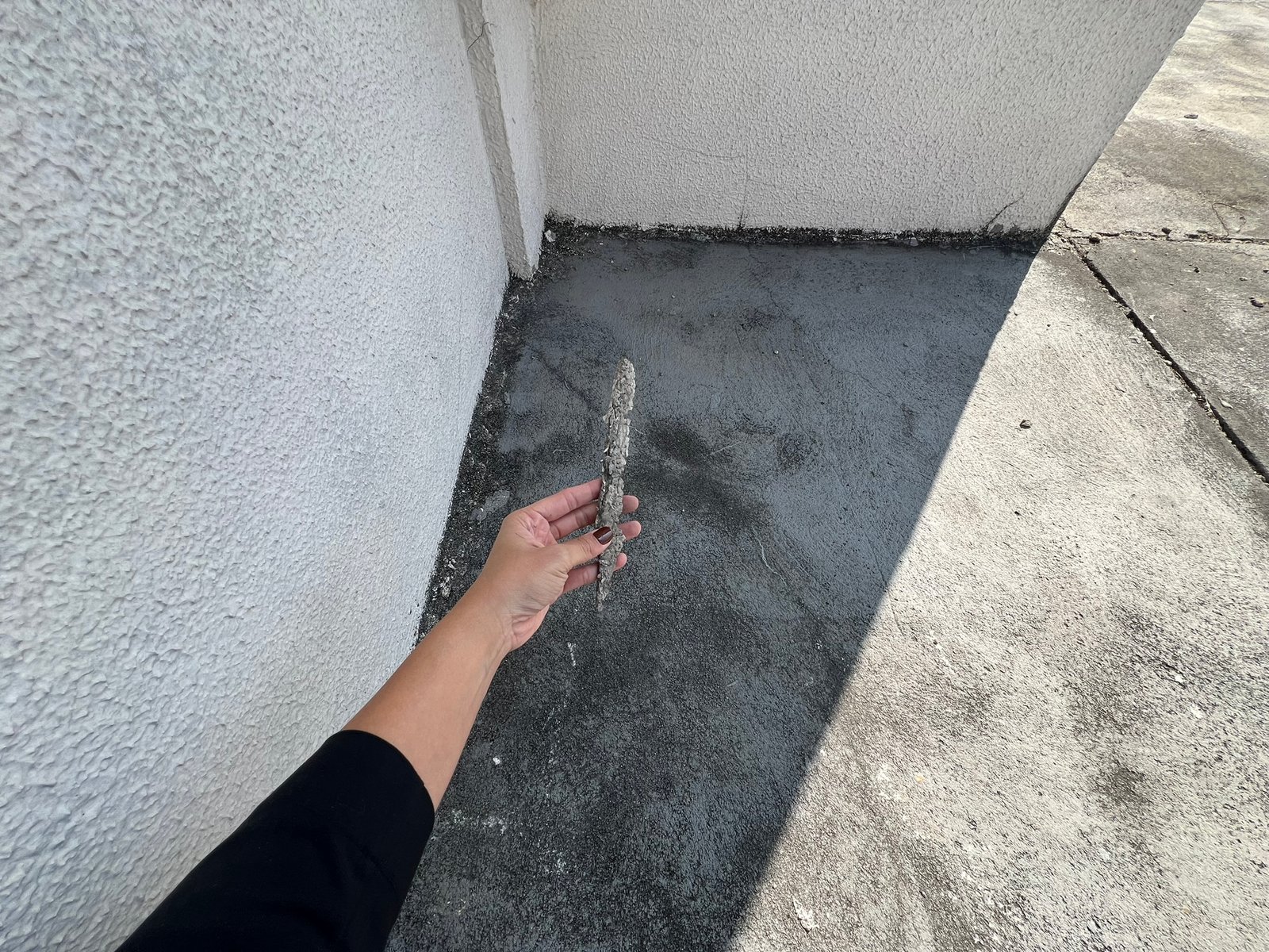 Desplacamento de revestimento em fachada com destacamento de material na base da parede.