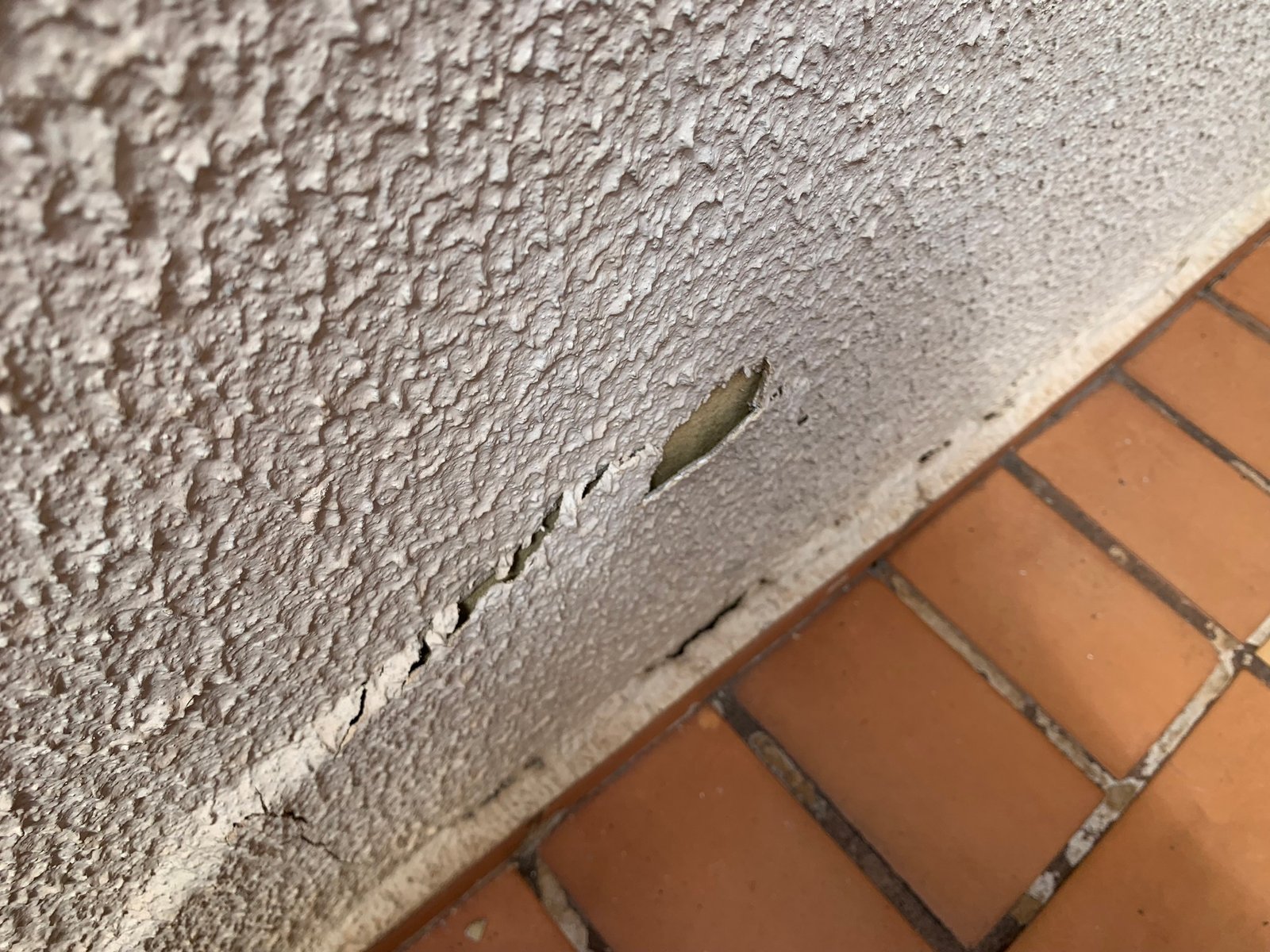 Rachadura perto do chão com o reboco da parede soltando