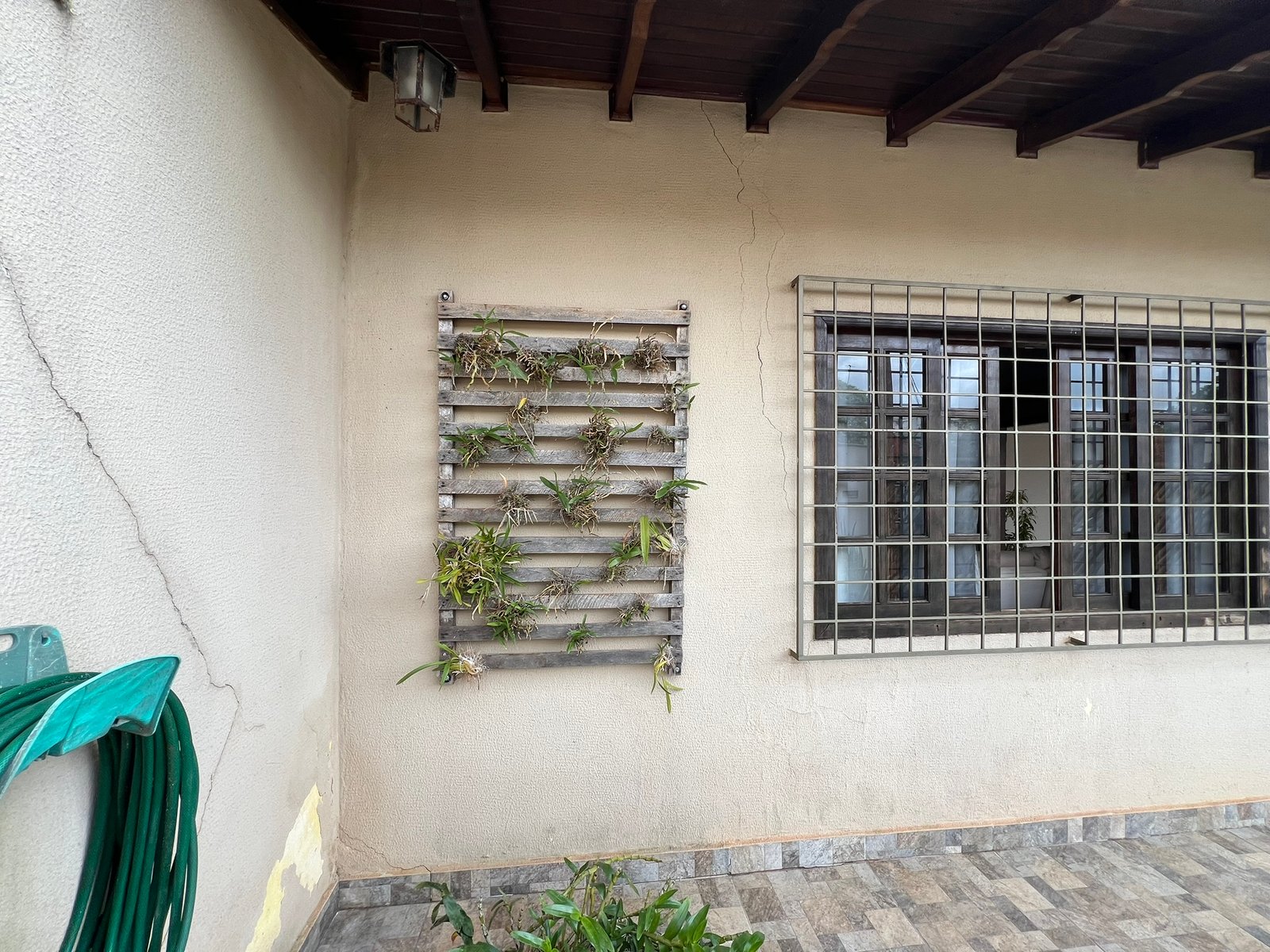 Rachadura diagonal na parede externa de uma casa, descendo inclinada
