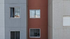 Fachada de edifício fotografada de perto por drone, com paredes nas cores cinza e terracota e janelas de alumínio