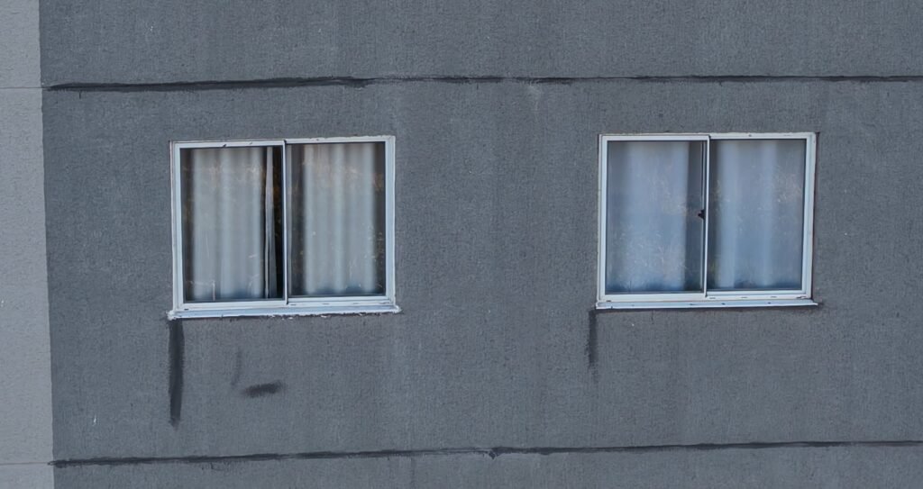 Fachada de edifício com escorrimento de água abaixo do peitoril da janela, foto aérea captada por drone