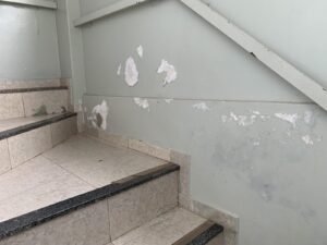 Parede de escada com revestimento descascando por umidade em vistoria técnica