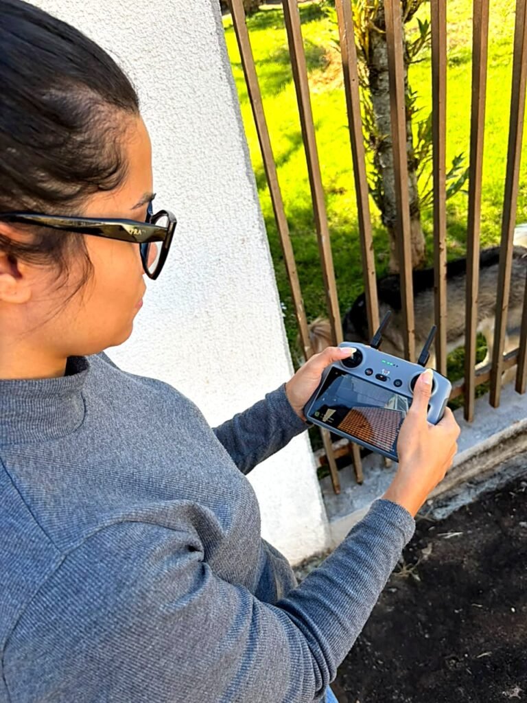 Engenheira segurando o controle do drone, com a tela mostrando as telhas do telhado em tempo real